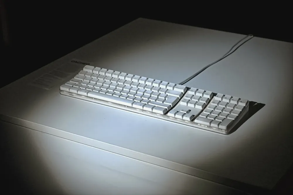 The keyboard alone under a pool of light on a pale table