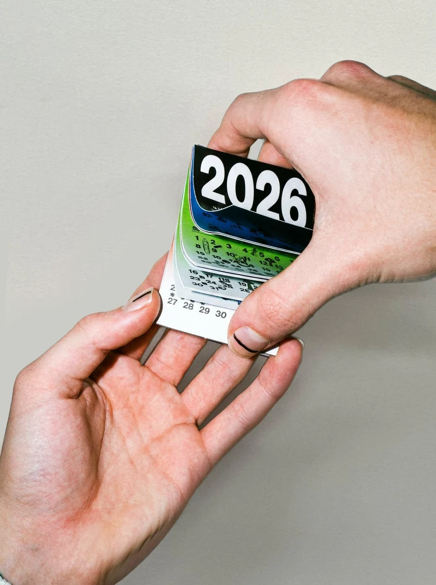 Two hands holding the closed calendar, showing its small scale