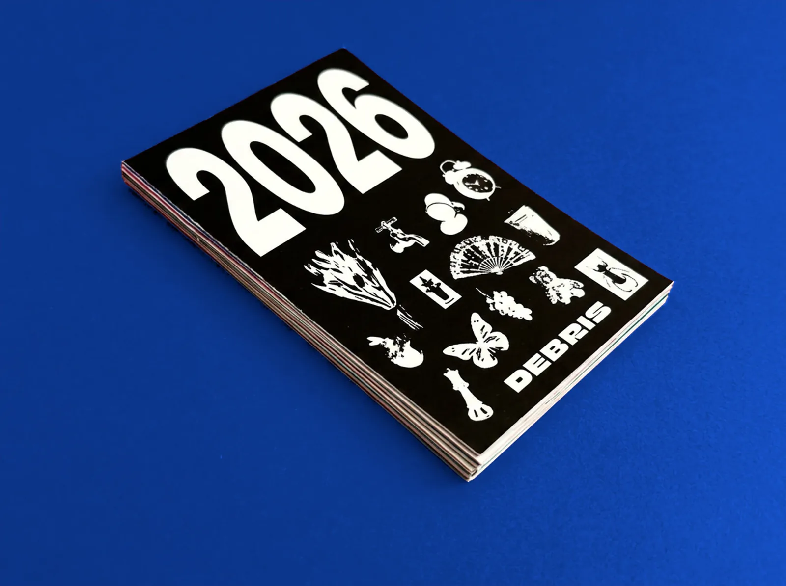 The calendar stack, 2026 cover facing up, on a deep blue surface