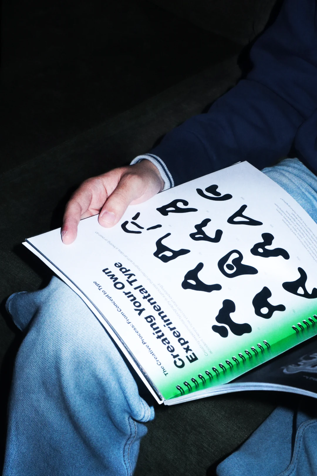 A spread of experimental type specimens on a green background, read on a lap