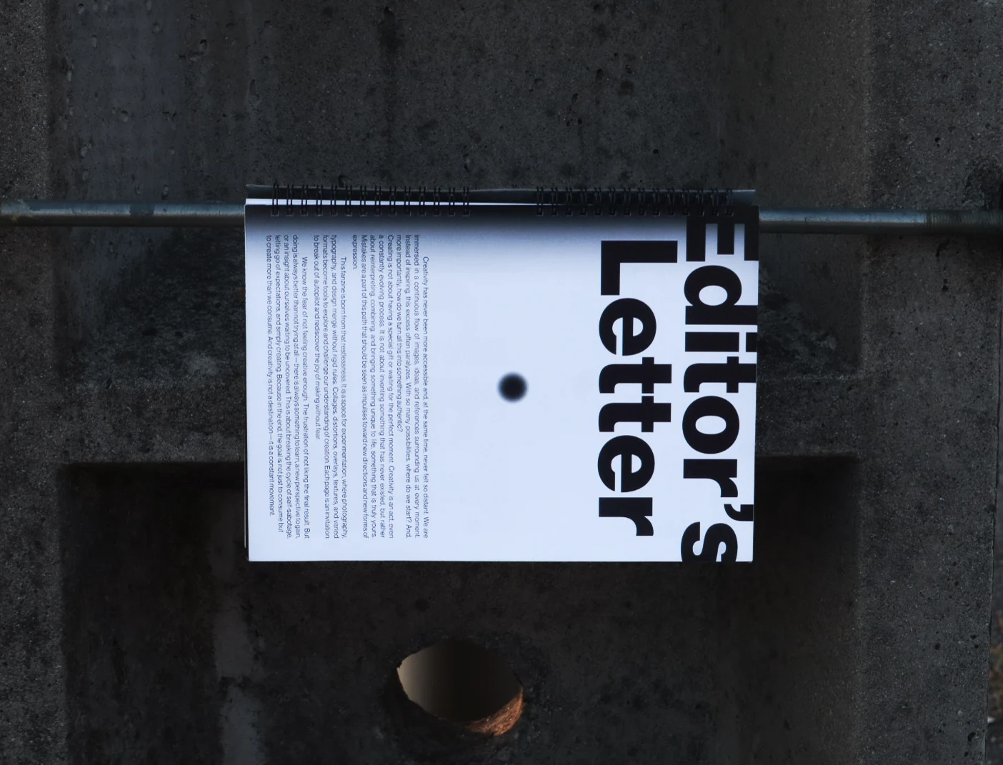 The “Editor’s Letter” page balanced on a metal rail against concrete